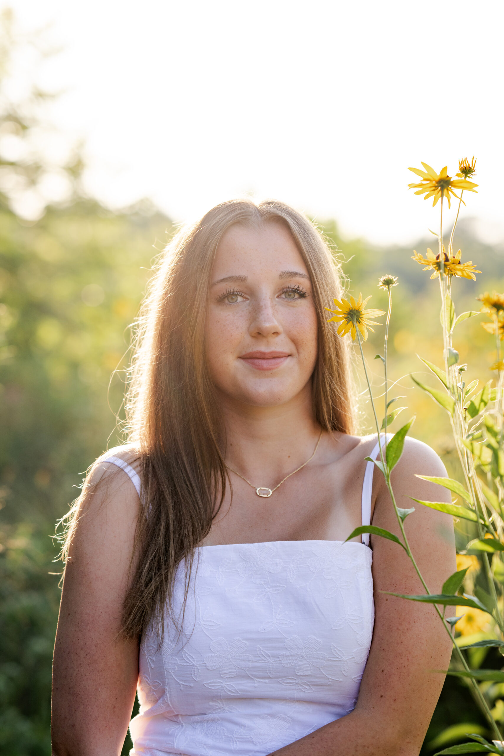High school senior girl poses beside yellow wildflowers at Newfields in Indianapolis during her portrait session with Kate Kosnoff Creative