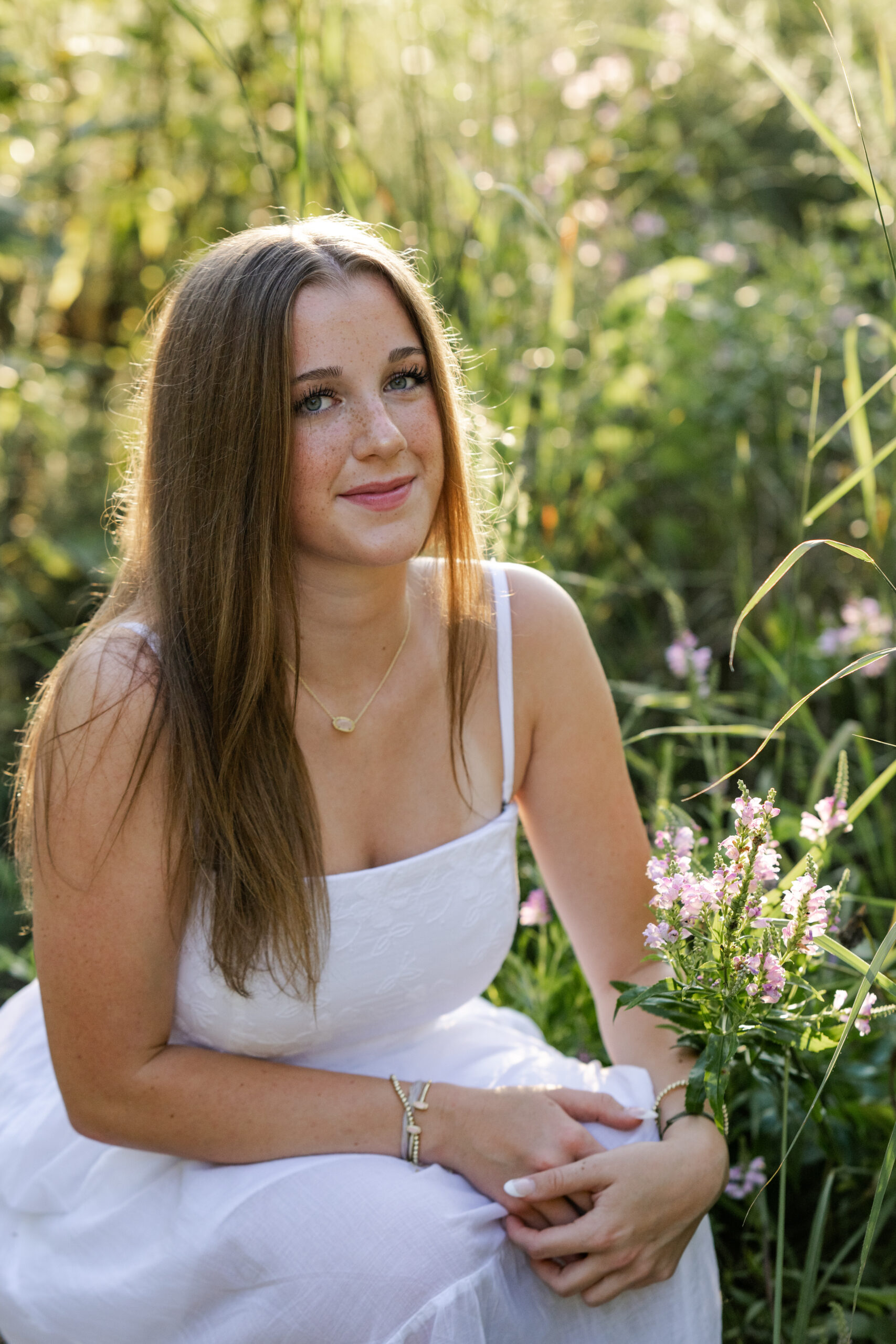 Brownsburg High School senior girl kneels among wildflowers during her spring senior photo session in Indianapolis